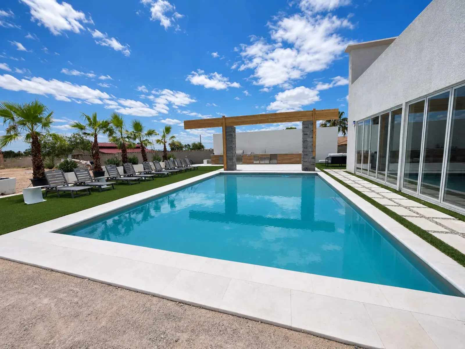 Heated pool lined with loungers and palm trees at the villa