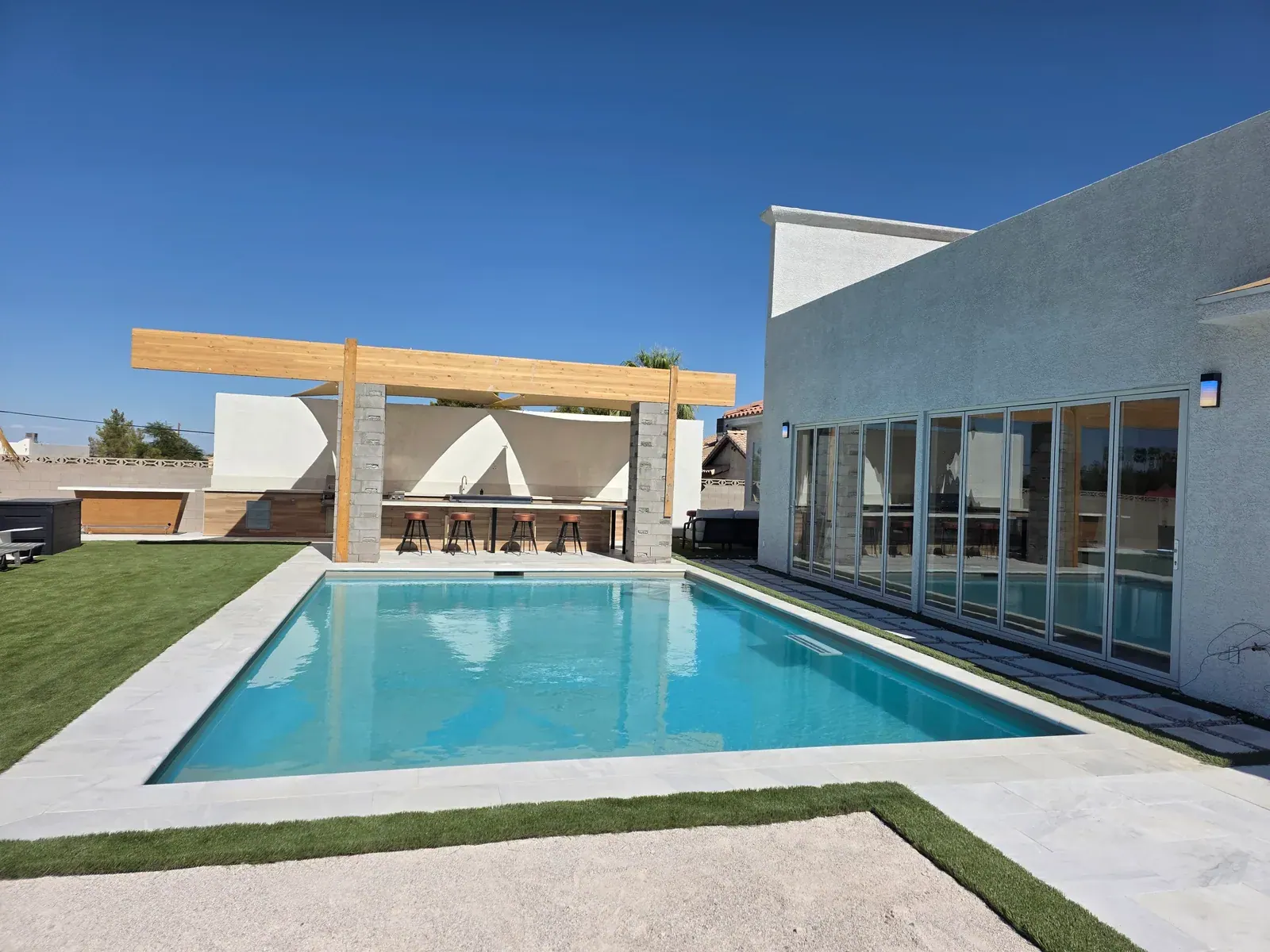 The heated pool with the pergola-covered outdoor kitchen beyond
